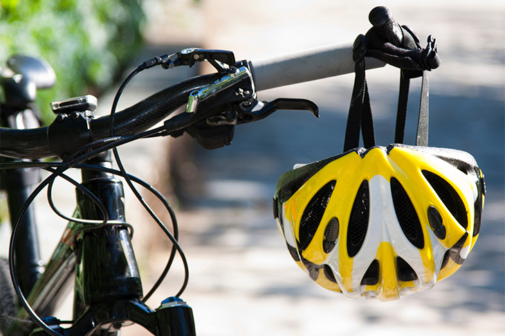 Cycling - helmet hanging on the handlebars of a bike (Canva)