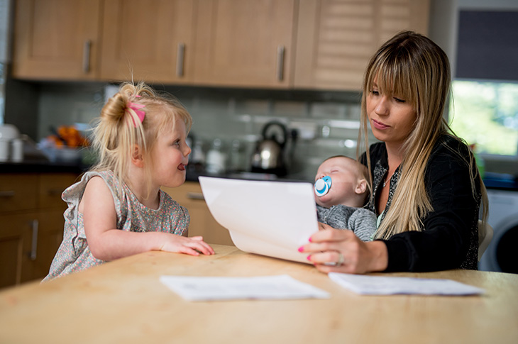 Woman holding a baby looking at a water bill (credit & copyright Southern Water & Darren Cool)